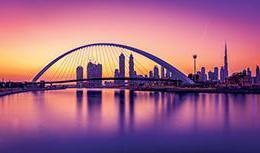 华丽的迪拜水渠和人行桥沐浴在紫色、粉色和橙色的日落之中