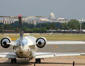 飞机在跑道上降落，背景是华盛顿特区的天际线，包括白宫