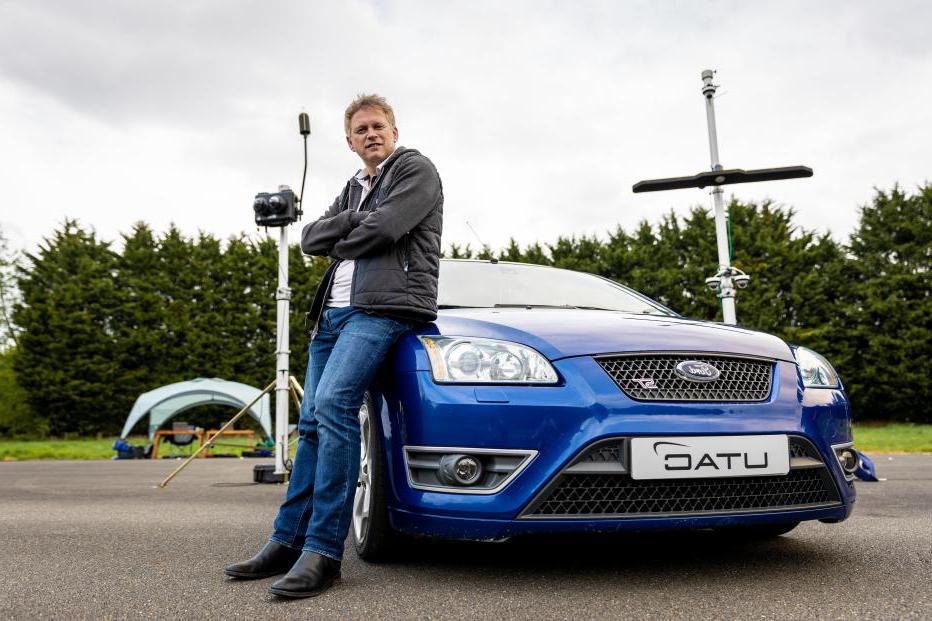 U.K. 运输部长格兰特·沙普斯坐在测试轨道上的蓝色汽车上