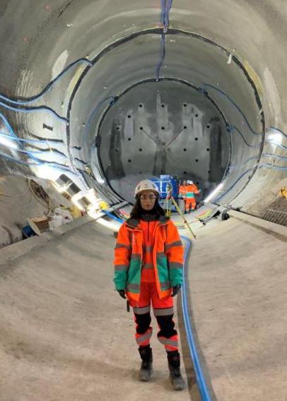 戴安全帽、身穿橙色工作服的女人站在巨大的隧道里
